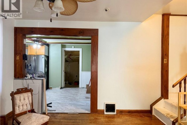 View from living room into kitchen and hallway, showing wooden trim and stairs. - 112 Arthur Street, Brantford