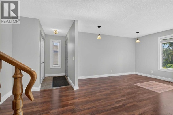 Interior view showing hallway entrance and part of the living area with wood flooring. - 112 Beaconsfield Rise Nw, Calgary