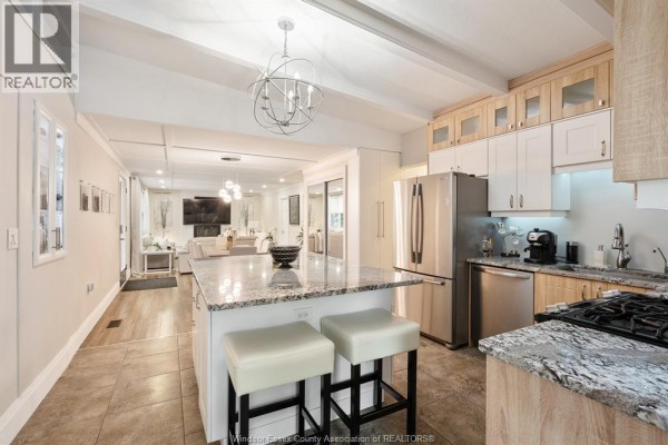 Modern kitchen with granite island, stainless steel appliances, and chandelier - 112 Clovelly Tecumseh