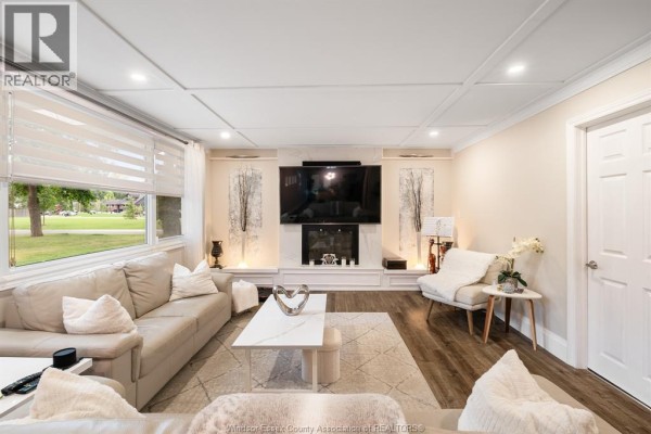 Living room with fireplace, TV, sectional sofa, accent chair, coffee table, and large window - 112 Clovelly Tecumseh
