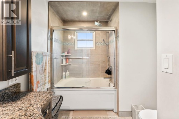 Bathroom with glass shower doors, tiled walls, and granite countertop - 112 Clovelly Tecumseh