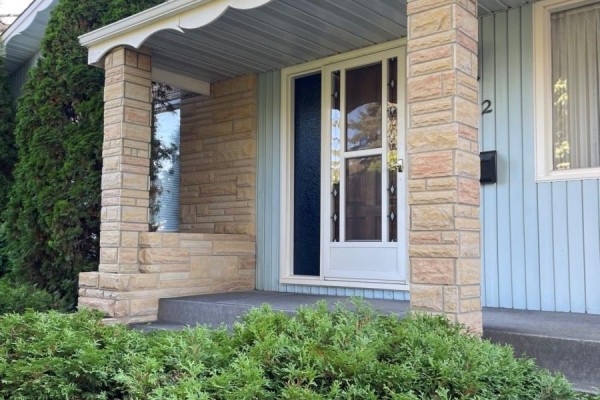 Detailed view of the home's front door with decorative glass and stone pillar. - 112 Deborah Crescent, Saskatoon