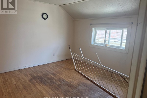 Bedroom with hardwood floors, a window, and a metal railing. - 112 Dwyer Avenue, Timmins