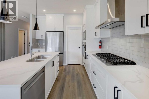 Kitchen featuring white cabinets, marble countertops, stainless steel appliances, and a gas stove. - 112 Emberside Place, Cochrane