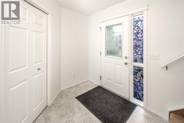 Interior foyer with a white front door, stained glass sidelight, and a closet. - 112 Everridge Drive Sw, Calgary