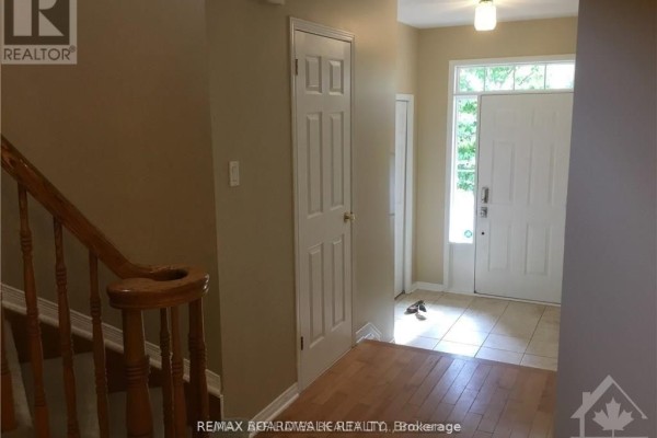 Foyer of the townhouse with a staircase, hardwood floors, and a white door. - 112 Gatespark Private Private E, Ottawa