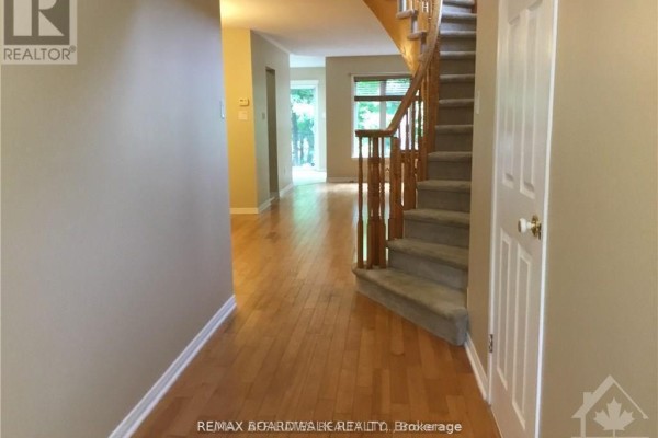 Hallway view showing hardwood floors, a staircase, and a doorway to the living area. - 112 Gatespark Private Private E, Ottawa