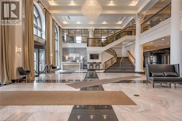 Grand building lobby with marble floors, grand staircase, chandelier, reception desk, and seating areas. - 112 King Street E Unit# Lph01, Hamilton