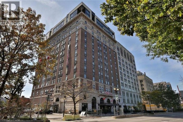Tall brick apartment building with stone accents and large arched windows, viewed from street level. - 112 King Street Unit# 1105, Hamilton