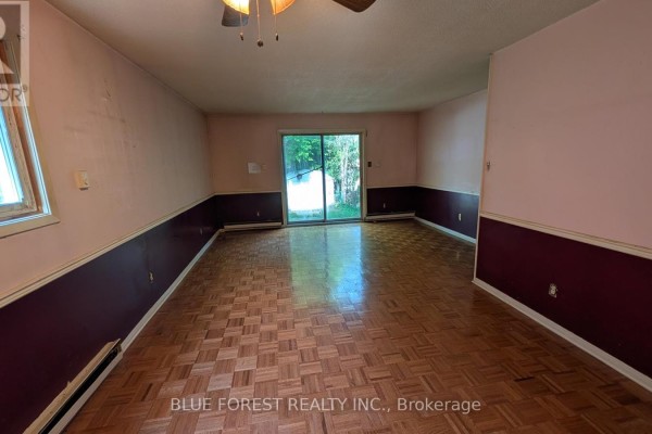 A large unfinished basement with carpeted floor, paneled ceiling, and two hanging light fixtures. - 112 Marlborough Avenue, London South