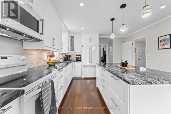 Modern kitchen with white cabinetry, dark granite countertops, and stainless steel appliances. - 112 Mary Avenue, Georgian Bluffs