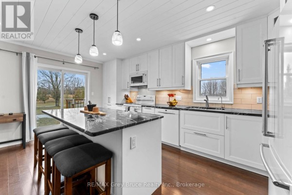 Open kitchen layout with island seating, pendant lighting, and white cabinetry. - 112 Mary Avenue, Georgian Bluffs