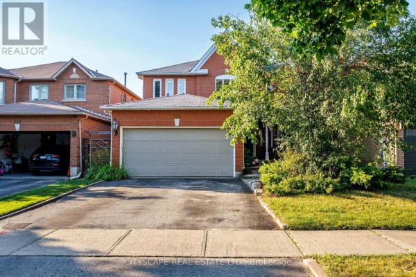 Close-up view of the red brick house exterior with a double garage door and green landscaping. - 112 Mulholland Drive, Vaughan