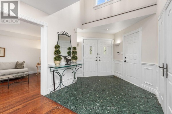 Interior foyer with a green terrazzo floor, white wainscoting, and double doors leading to a living room. - 112 Mulholland Drive, Vaughan