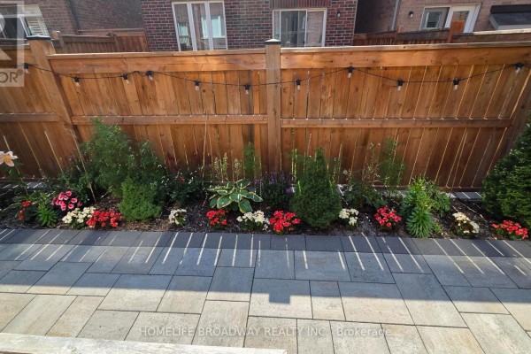 Paved backyard patio with dining furniture and landscaping enclosed by a wooden fence. - 112 Ness Drive, Richmond Hill