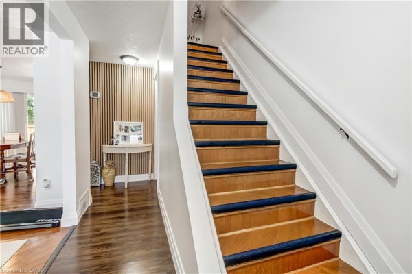 Wooden staircase with white railings and dark blue stair treads inside the townhouse. - 112 Richardson Drive Unit# 24, Port Dover