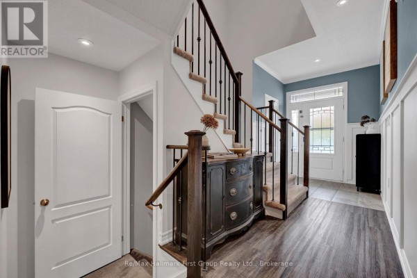 Interior view of foyer with staircase, wainscoting, and entryway door. - 112 Roy Nichols Drive, Clarington