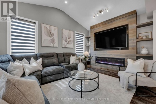 Living room featuring a sectional sofa, fireplace, mounted television, and accent wall. - 112 Roy Nichols Drive, Clarington