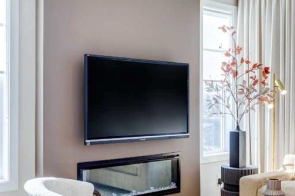 Wall-mounted television above a modern fireplace with glass stones in a living room. - 112 Southbow Avenue, Cochrane