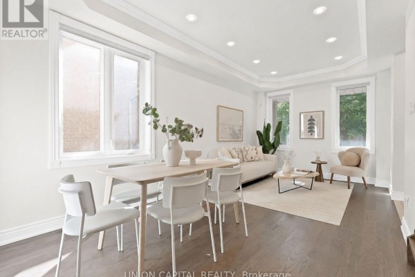 Bright dining area with a white table and chairs, leading into a living room with a sofa. - 112 Southbrook Crescent, Markham