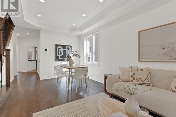 Open-concept living and dining space with dark wood floors, white walls, and a staircase. - 112 Southbrook Crescent, Markham