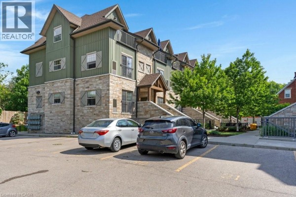 Parking area in front of the apartment building with two cars parked. - 112 Union Street E Unit# B103, Waterloo