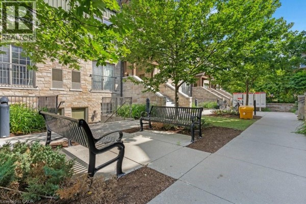 Outdoor seating area with benches and landscaping in front of the apartment building. - 112 Union Street E Unit# B103, Waterloo
