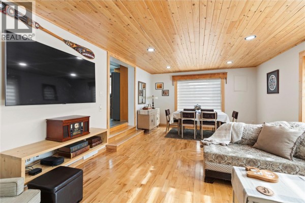 Living room featuring wooden ceiling, large TV, and dining area with a table. - 112 Walker Road, Clearwater