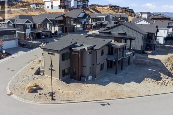 Rear exterior of a modern house showing multiple windows, balconies, and a lower level. - 1120 Collinson Court, Kelowna