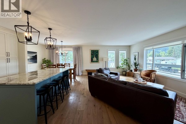 Open concept living and dining area with a kitchen island, comfortable seating, and large windows. - 1120 Toronto Street, Smithers