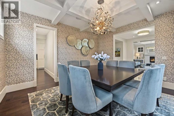 Dining room with a dark wood table, light blue upholstered chairs, patterned wallpaper, and chandelier. - 1121 Valois Avenue Sw, Calgary