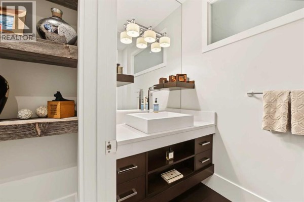 Powder room with a white vessel sink, dark wood vanity, and rustic open shelving. - 1121 Valois Avenue Sw, Calgary
