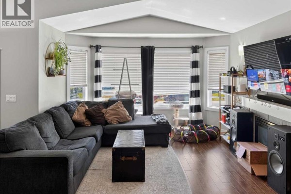 A bedroom with a floral comforter on the bed and doorways to other rooms. - 11212 75a Avenue, Grande Prairie