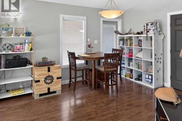 A hallway with several doors opening into rooms with dark trim and wood floors. - 11212 75a Avenue, Grande Prairie