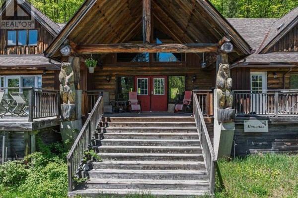 Close-up of the wooden entrance stairs to the log home, flanked by carved bear statues. - 1123 Dardanelles Road, Dysart Et Al