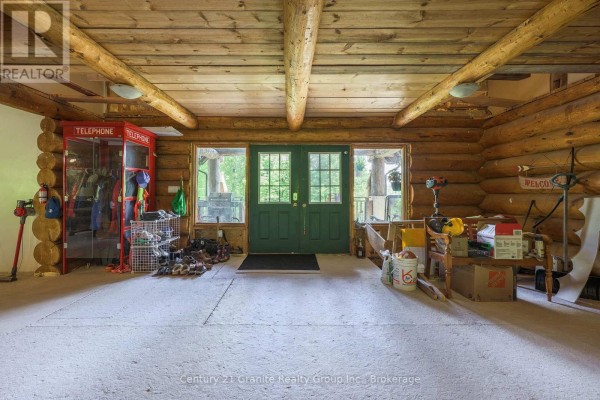 Interior view of a log home entrance with double green doors, red telephone booths, and concrete floor. - 1123 Dardanelles Road, Dysart Et Al