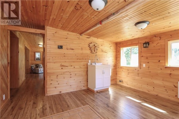 Interior room with light wood paneling, a sink vanity, and two windows overlooking the outdoors. - 1123 Regional Road 10, Whitefish