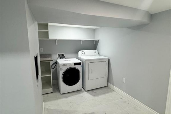 A laundry room with a white washing machine and dryer, and open shelving above. - 1124 Janette Avenue Unit# Lower, Windsor