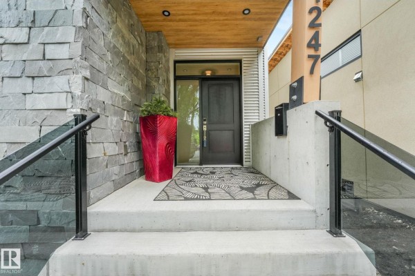 Dining room with wood floors, modern light fixture, and view of staircase. - 11247 71 Av Nw, Edmonton