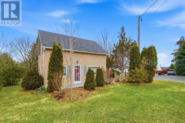Living room with grey walls, wood floors, multiple recliners, and a blue wood stove. - 1125 County Rd 1 E, Stone Mills