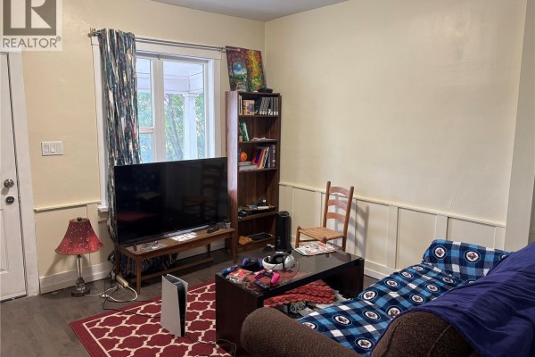 Living room with a couch, coffee table, television, and bookshelf. - 1125 Idylwyld Drive N, Saskatoon