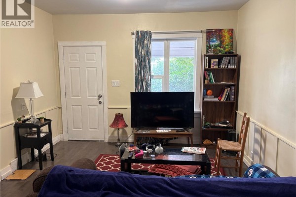 Living room facing the entrance door with a couch, coffee table, and television. - 1125 Idylwyld Drive N, Saskatoon