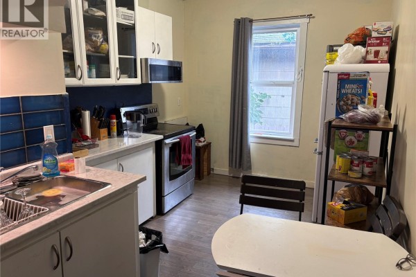 Kitchen with white cabinets, stainless steel appliances, and a small dining table. - 1125 Idylwyld Drive N, Saskatoon
