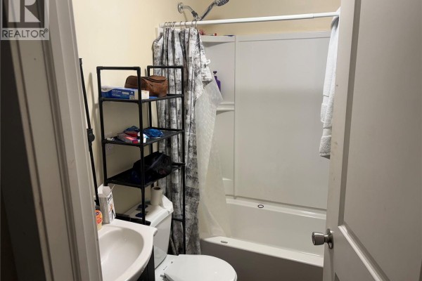 Bathroom with a white bathtub, toilet, sink, and shower curtain. - 1125 Idylwyld Drive N, Saskatoon