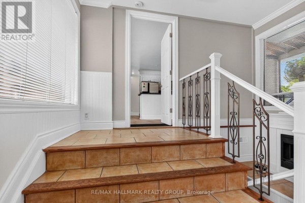 Front door entrance with a window, tiled steps, and decorative metal banister. - 1125 Kenaston Street, Ottawa