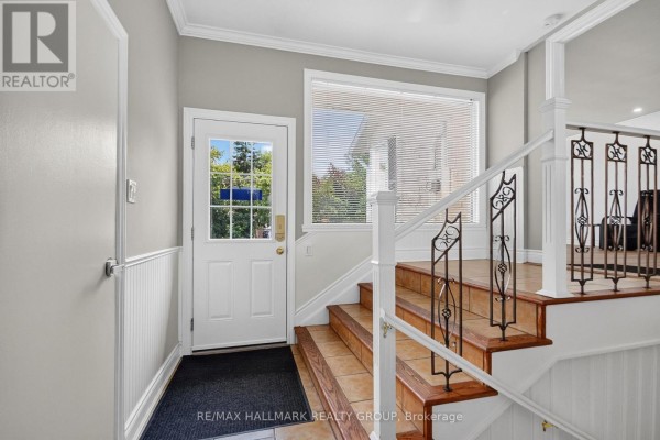 Living room with white walls, wood-look flooring, and large corner windows. - 1125 Kenaston Street, Ottawa