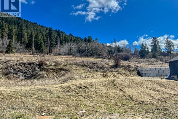 Cleared land with wooden fencing, surrounded by trees and hills in the background. - 1126 12th Avenue N, Creston