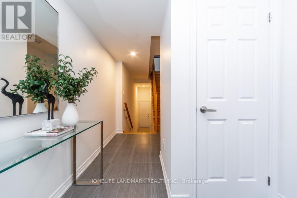 Interior hallway with grey tile floors, a white door, and a glass console table. - 1126 Baltic Lane, Pickering