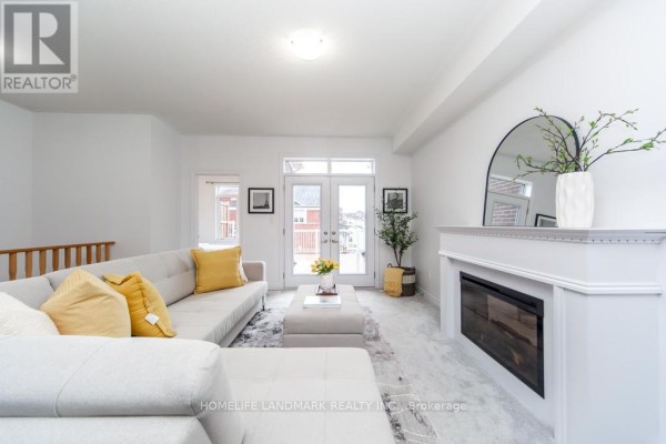Living room with a sectional sofa, fireplace, and double doors opening to a balcony. - 1126 Baltic Lane, Pickering