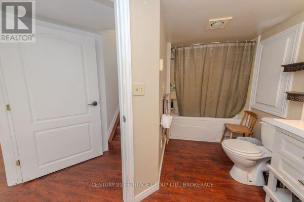 Bathroom with tub, toilet, vanity, and wood-look flooring - 1127 Perry Lane Frontenac
